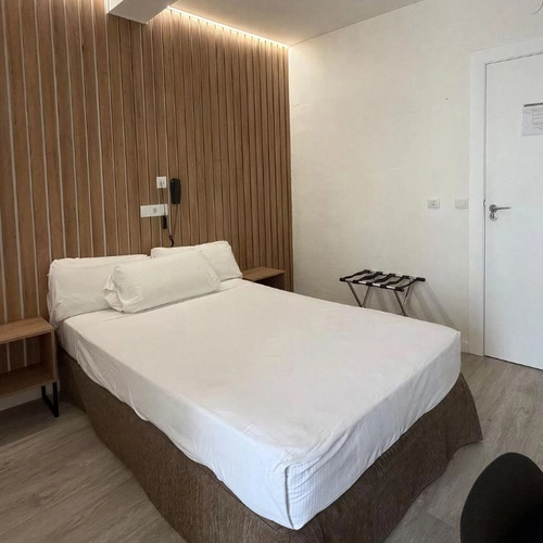 Habitación cómoda con cama doble,Hotel Victoria Centro, mesitas de noche y armario de equipaje.