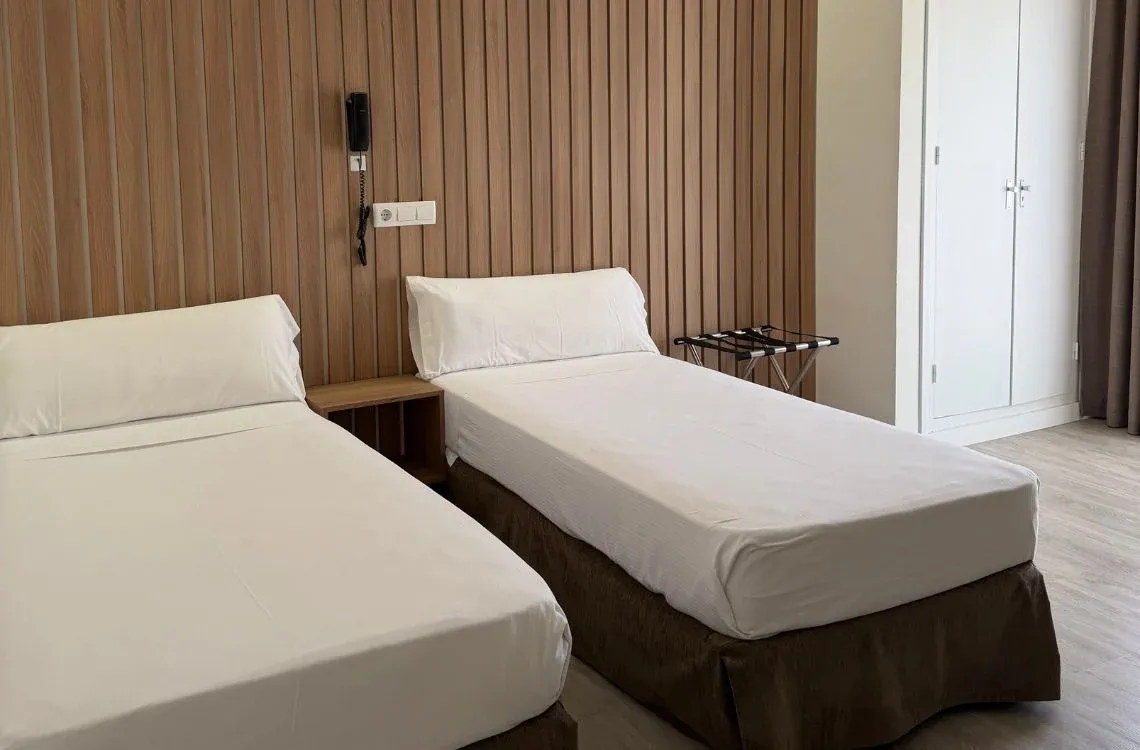 Habitación doble con dos camas individuales, mesita de noche, armario y teléfono. Hotel Victoria Centro