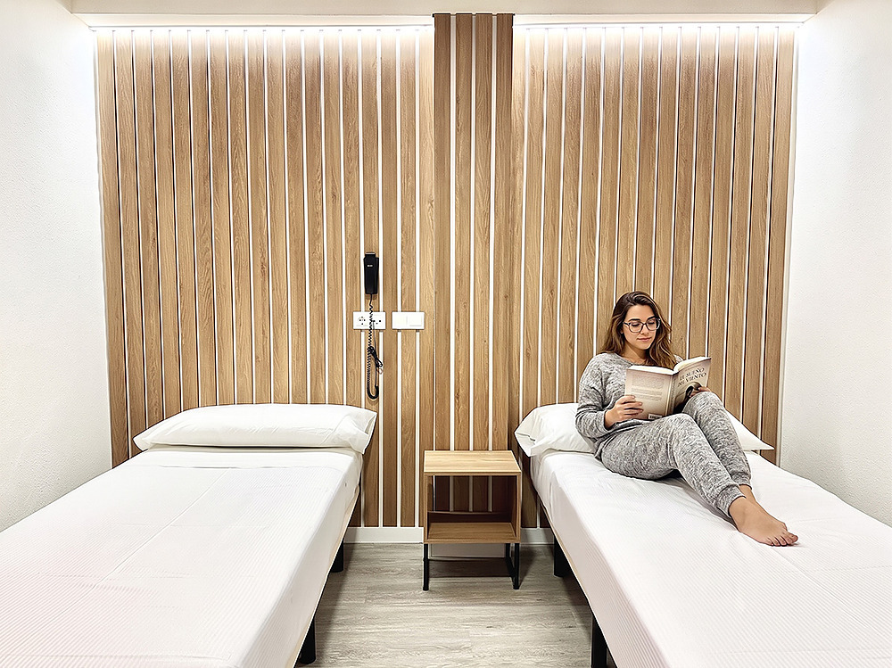 Habitación con dos camas, una mujer leyendo Hotel Victoria Centro en la cama de la derecha.