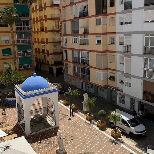 Fachada de hotel con Hotel Victoria Centro, patio andaluz con fuente azul y palmeras.