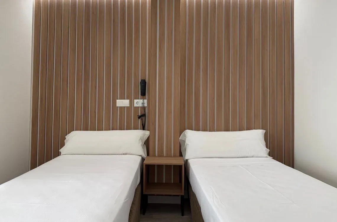 Habitación doble con camas individuales,Hotel Victoria Centro y pared de lamas de madera.
