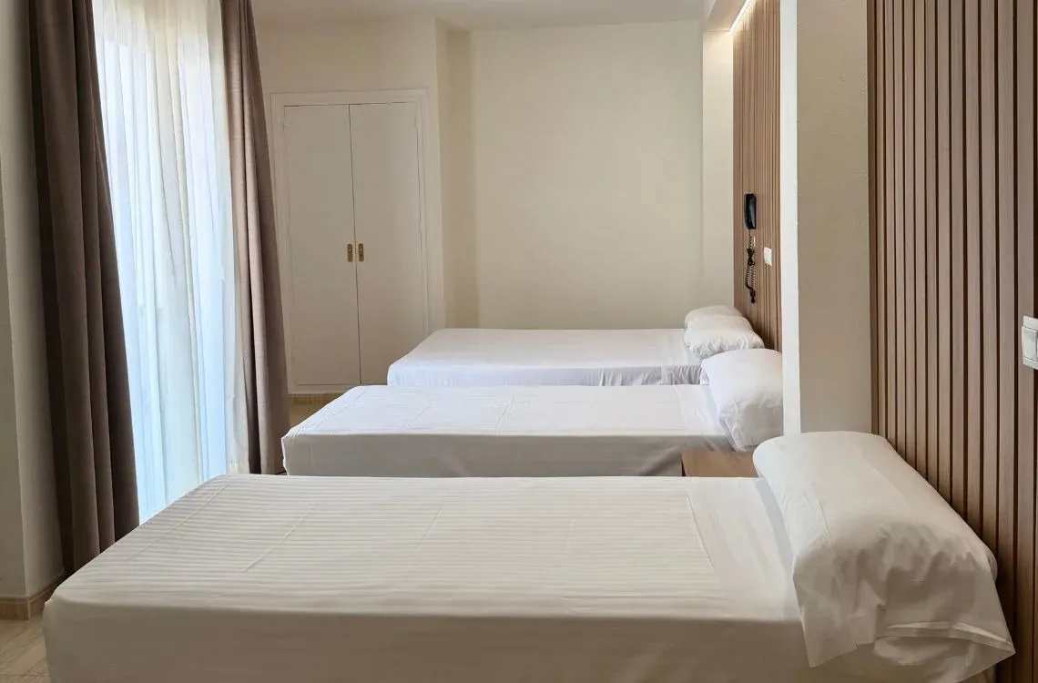 Habitación triple con tres camas individuales y textiles blancos. Hotel Victoria Centro