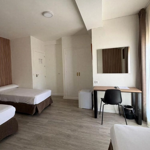 Habitación de hotel con dos camas, escritorio, espejo y mininevera. Hotel Victoria Centro