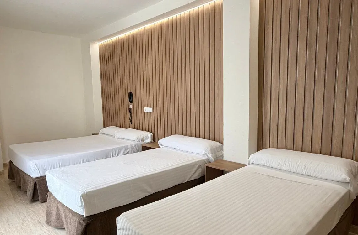 Habitación triple con camas individuales y cabeceros de madera, ideal para grupos o familias. Hotel Victoria Centro