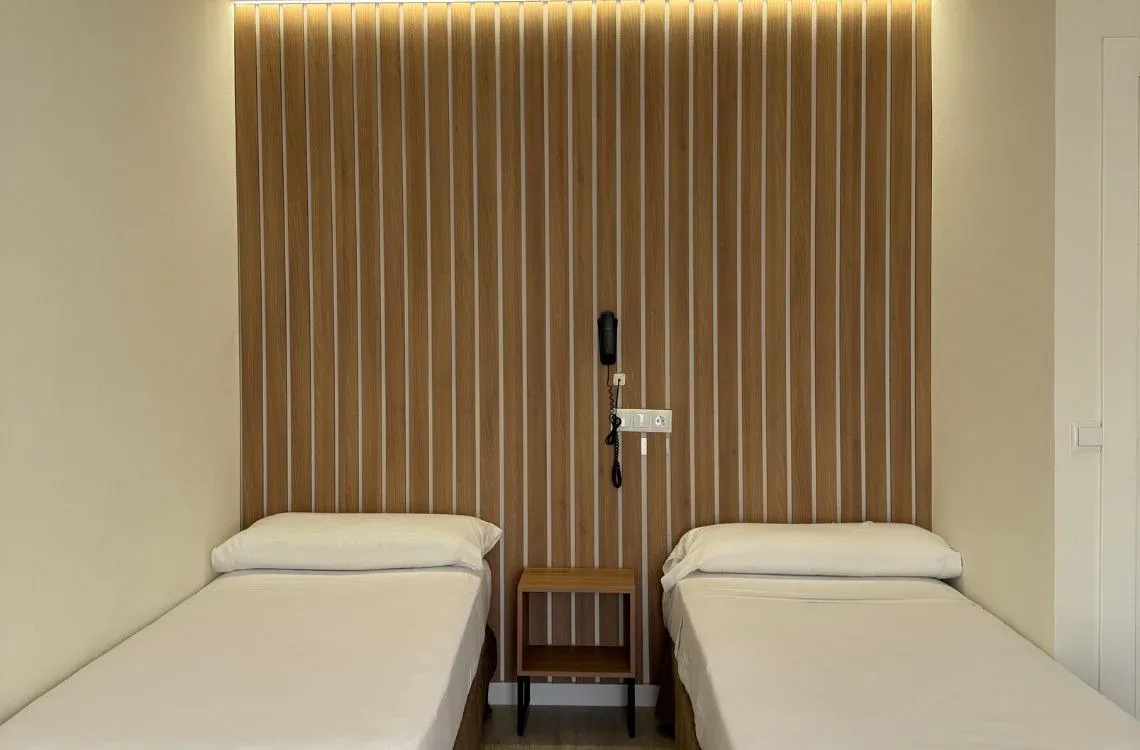 Habitación doble con camas individuales, decoración moderna y teléfono, ideal para tu Hotel Victoria Centro.