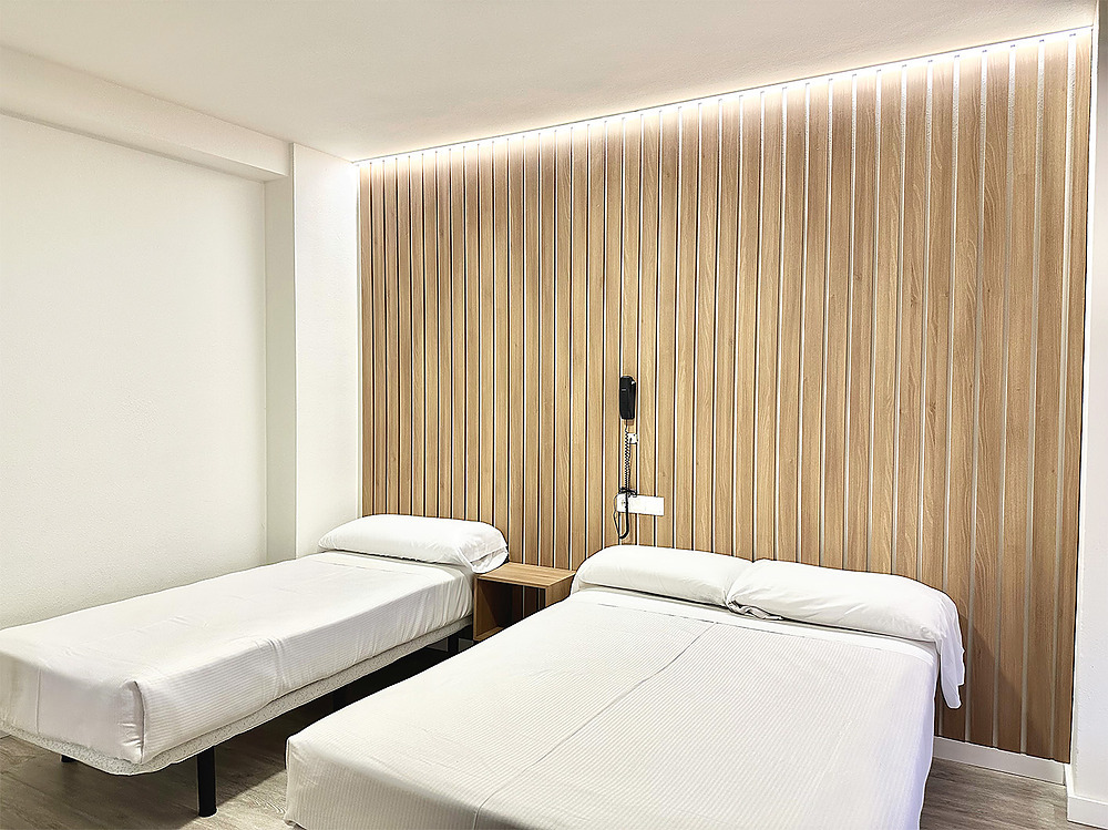 Habitación moderna con dos camas, panel de madera y luz LED. Hotel Victoria Centro