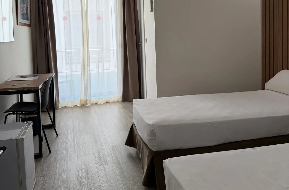 Habitación con dos camas individuales, escritorio y balcón. Hotel Victoria Centro