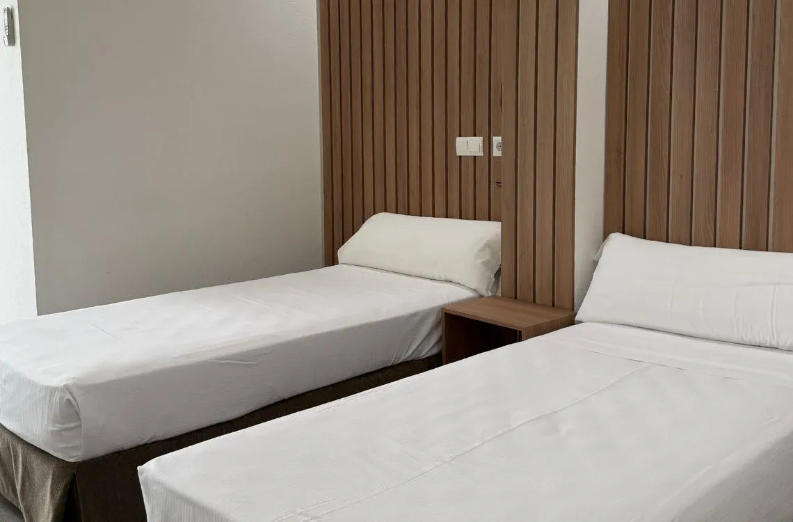 Habitación de hotel con dos camas individuales yHotel Victoria Centro modernas.