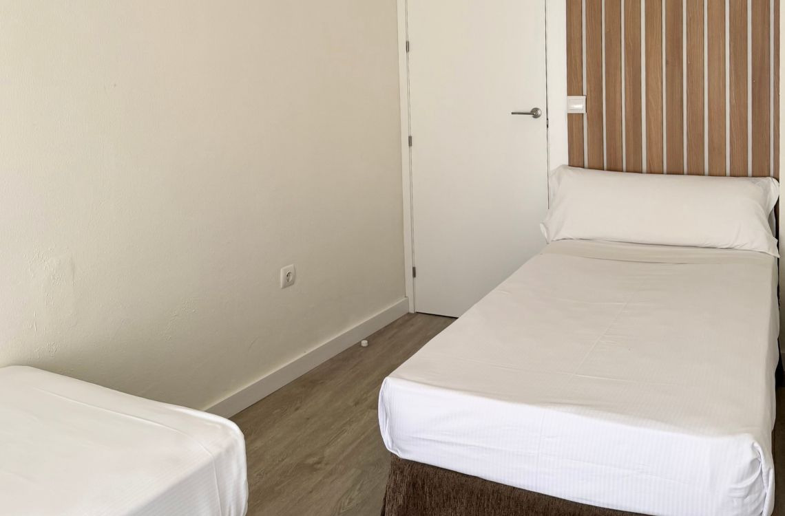 Habitación con dos camas individuales, armario de madera y baño privado. Hotel Victoria Centro