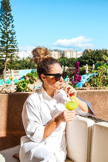 a woman sitting on a couch drinking a drink with a straw