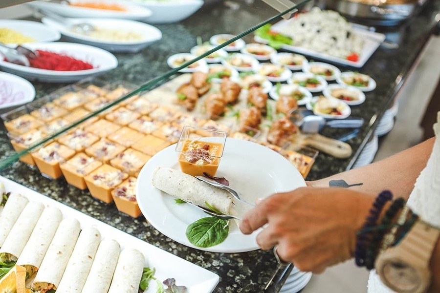 a person taking a plate of food from a buffet