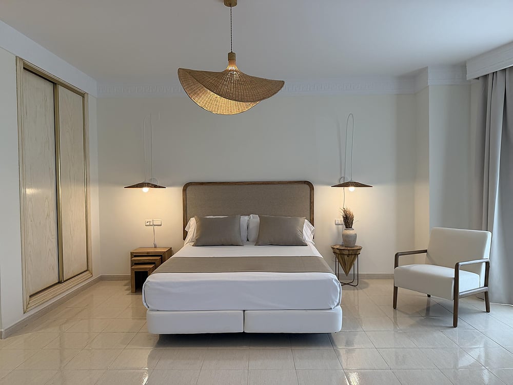 Comfortable hotel bedroom with a large bed, bedside tables, and a cozy chair. Victoria Playa