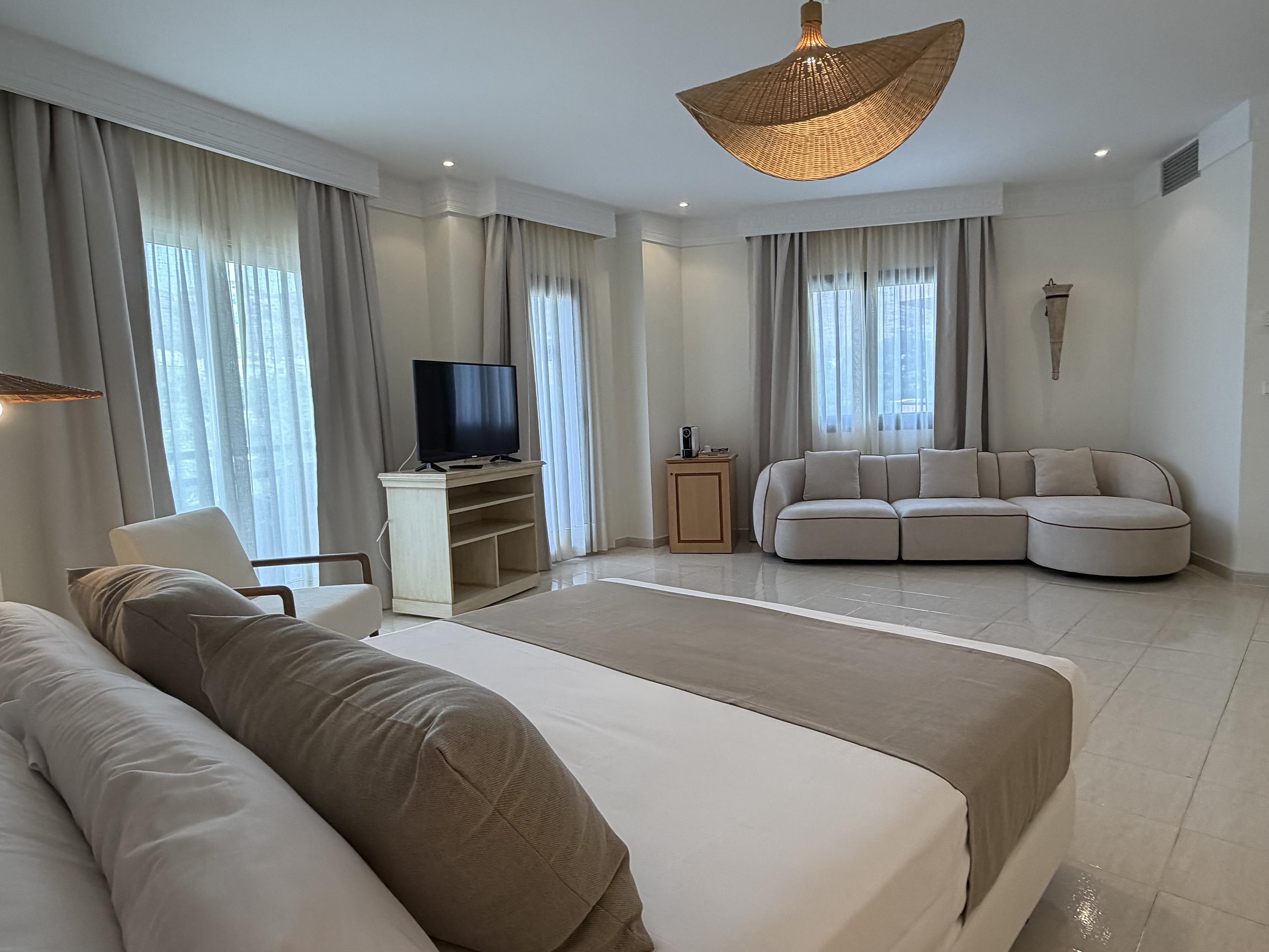 Suite espaciosa Victoria Playa con cama king, sofá rojo y balcón.