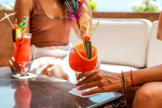 a woman is holding a red cocktail with a straw in it