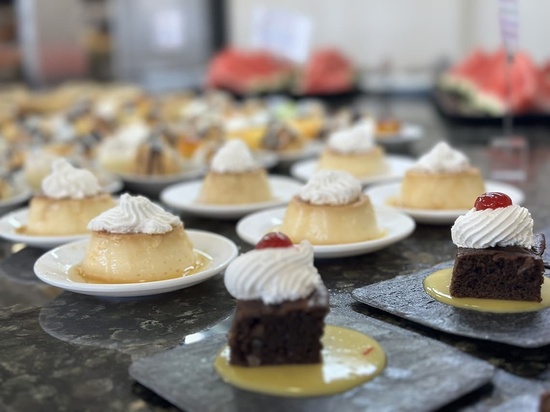 a display of desserts including a brownie with whipped cream and a cherry on top