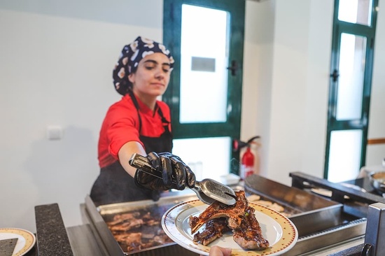 una mujer sostiene un tenedor sobre un plato de carne