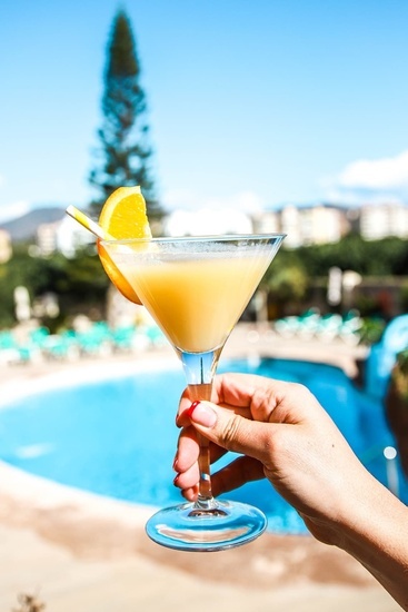 a person holding a martini glass with an orange slice in it