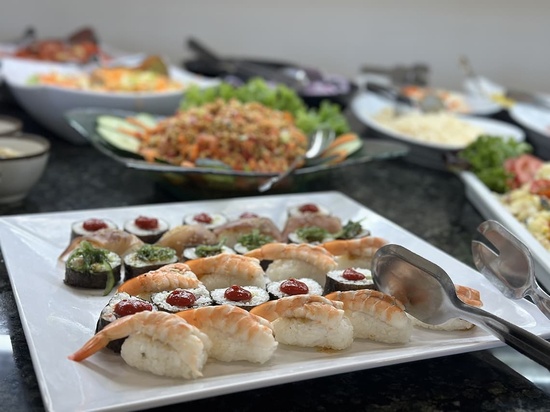 a plate of sushi with shrimp and tomatoes on top