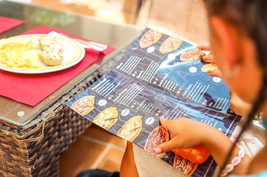 una persona está mirando un menú de pizzas en un restaurante