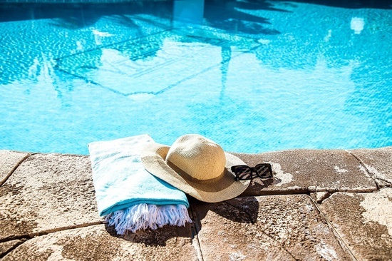 una toalla , sombrero y gafas de sol junto a una piscina