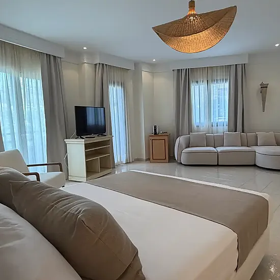 Suite espaciosa con cama king en Victoria Playa, sala de estar, sofá rojo y vistas.