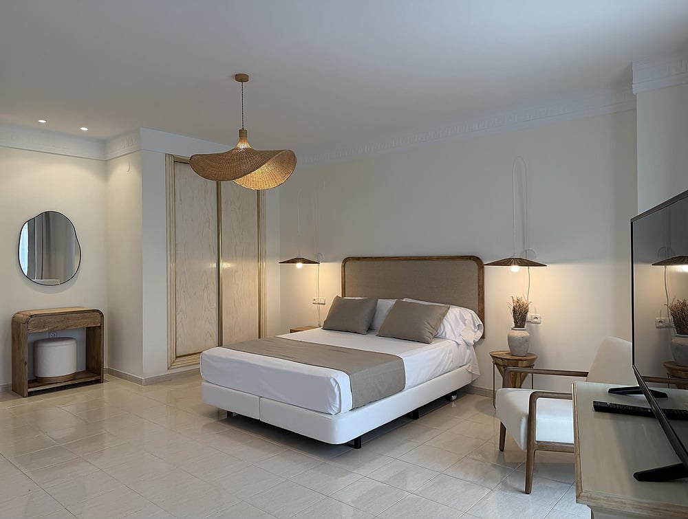 Modern hotel bedroom with king Victoria Playa, natural light, and minimalist decor.