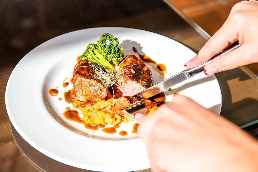 a person is cutting a piece of meat on a plate