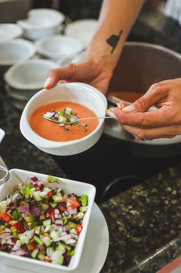 a woman with a tattoo on her arm is pouring soup into a bowl