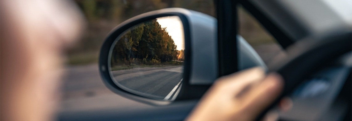 una persona está conduciendo un automóvil y mirando en el espejo retrovisor .