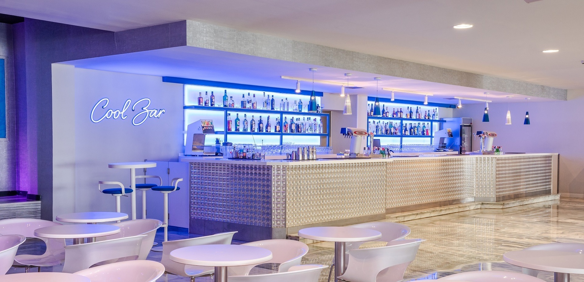 un bar con tavoli e sedie e un neon che dice cool bar