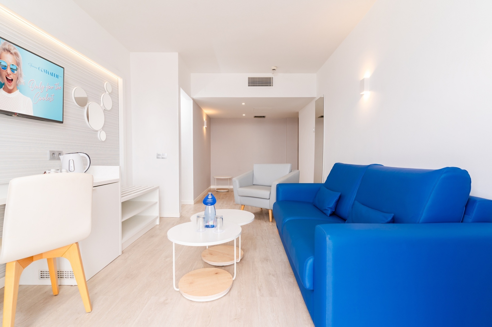 a living room with a blue couch and two white tables