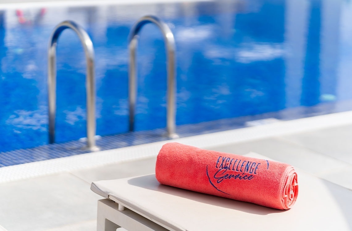 une piscine entourée de chaises longues et d' ombrelles avec des serviettes rouges à côté d' elle