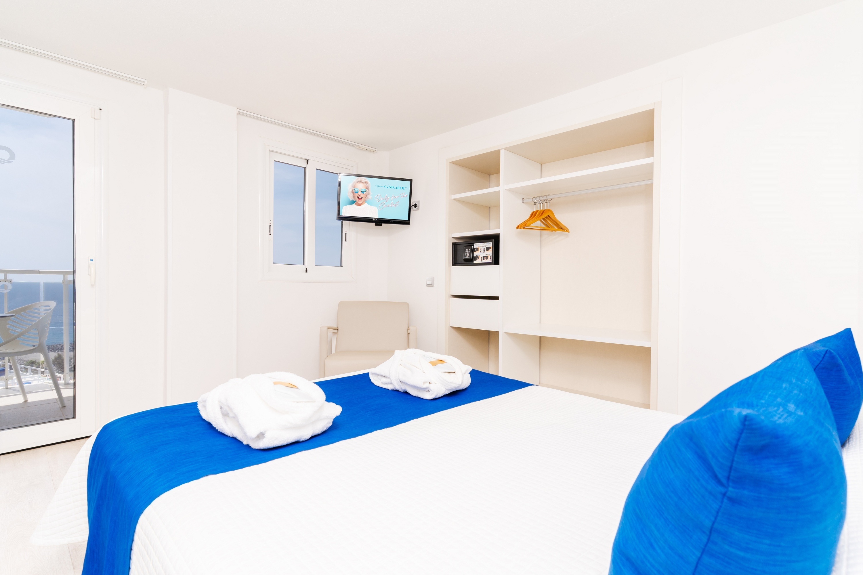a hotel room with a blue and white bed and a flat screen tv