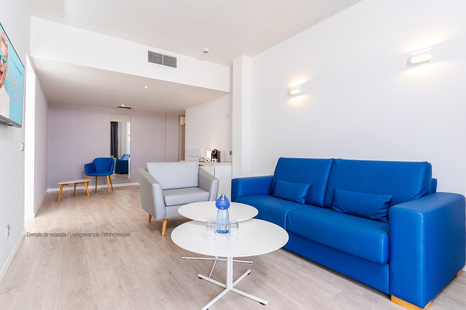 a living room with a blue couch and two white tables