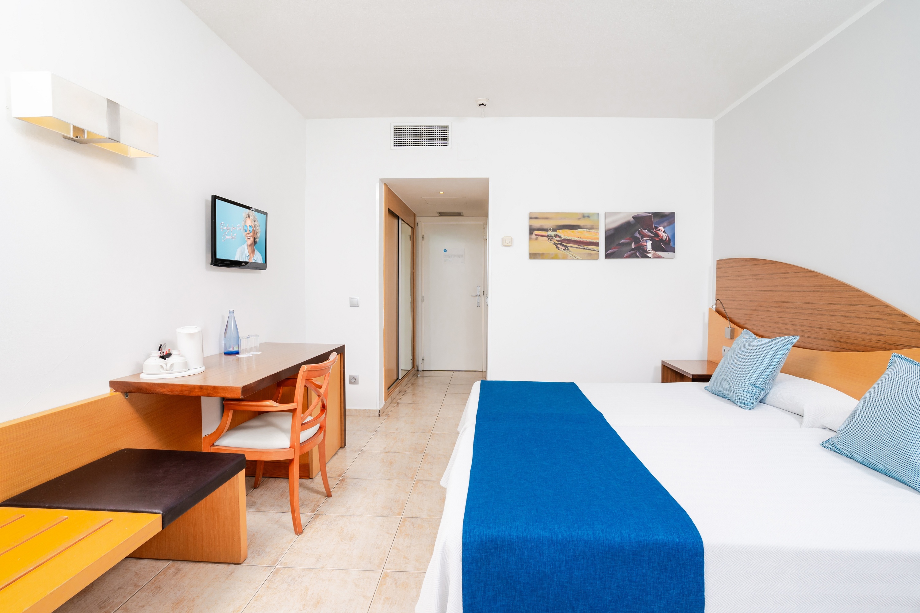 una camera d' albergo con un letto bianco e cuscini blu