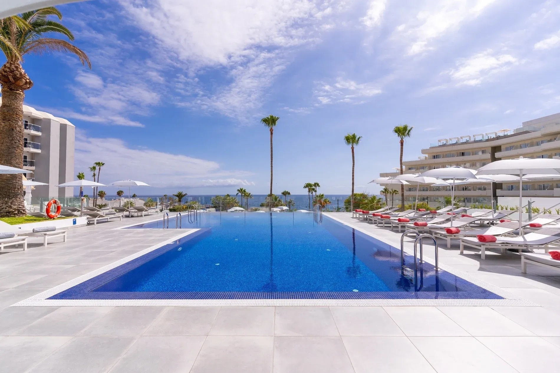 una grande piscina circondata da sedie e ombrelloni in un hotel