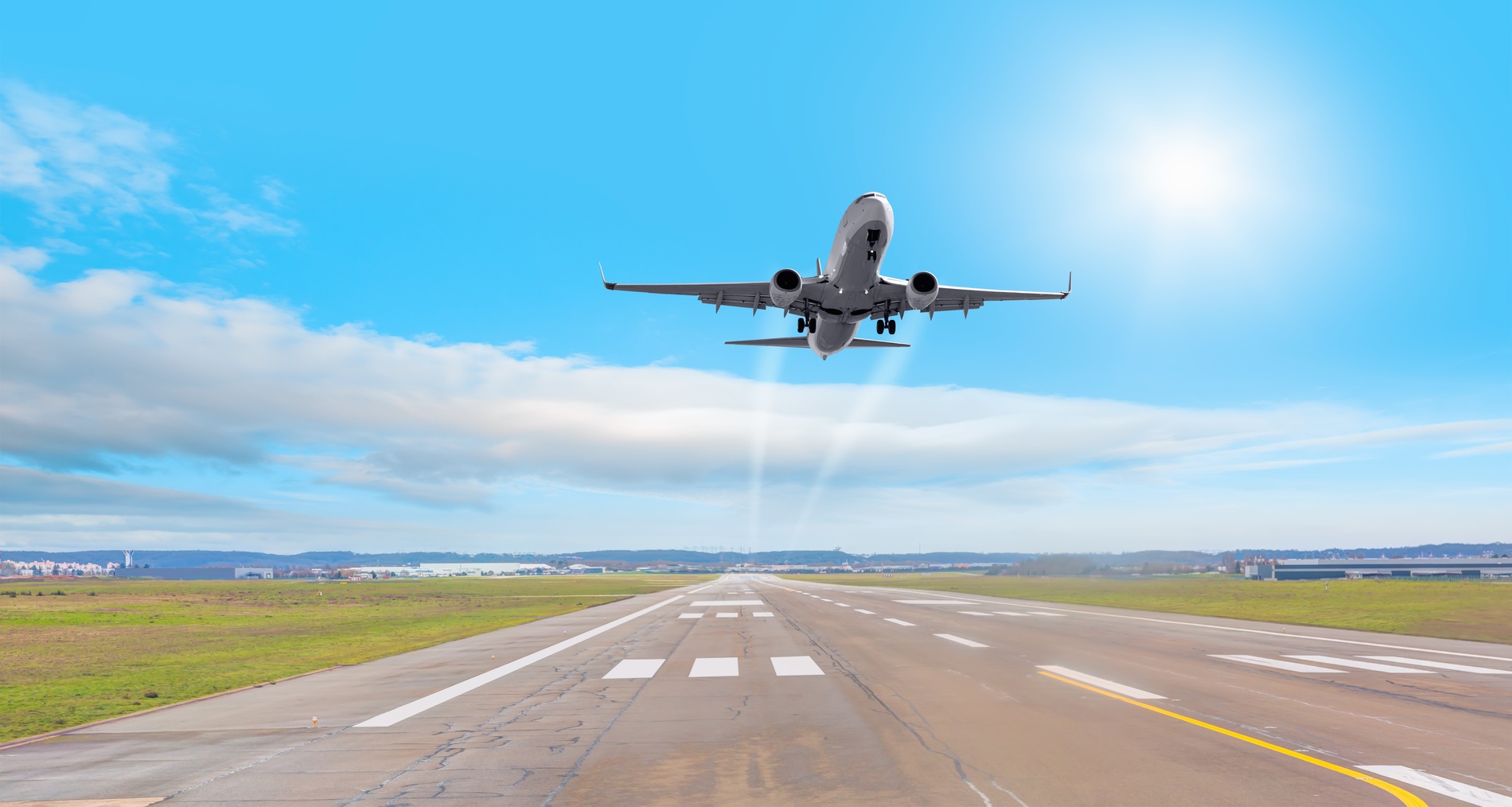 una mujer sostiene una chaqueta marrón mientras camina con una maleta blanca