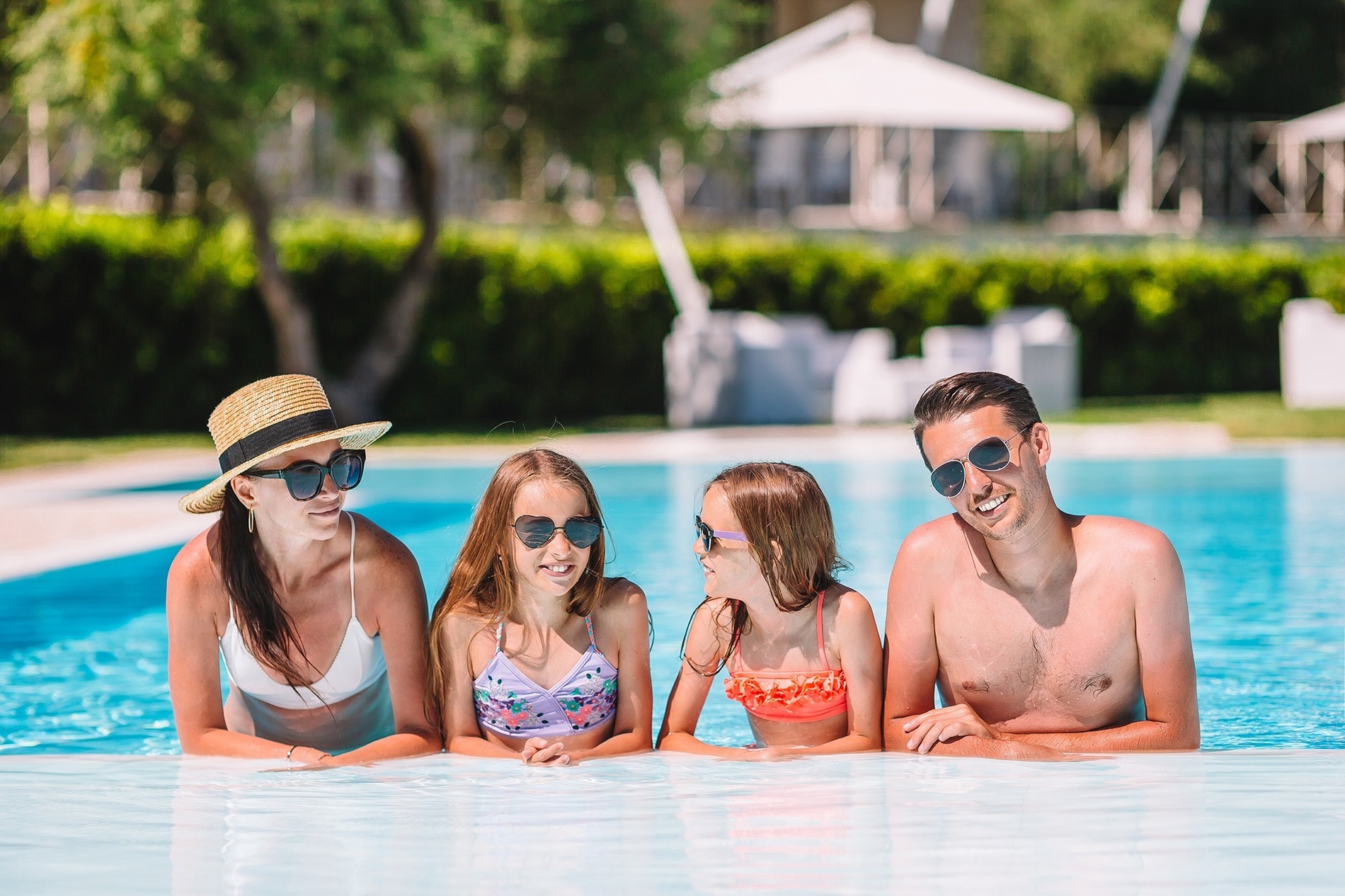 семья в купальниках и солнцезащитных очках лежит в бассейне