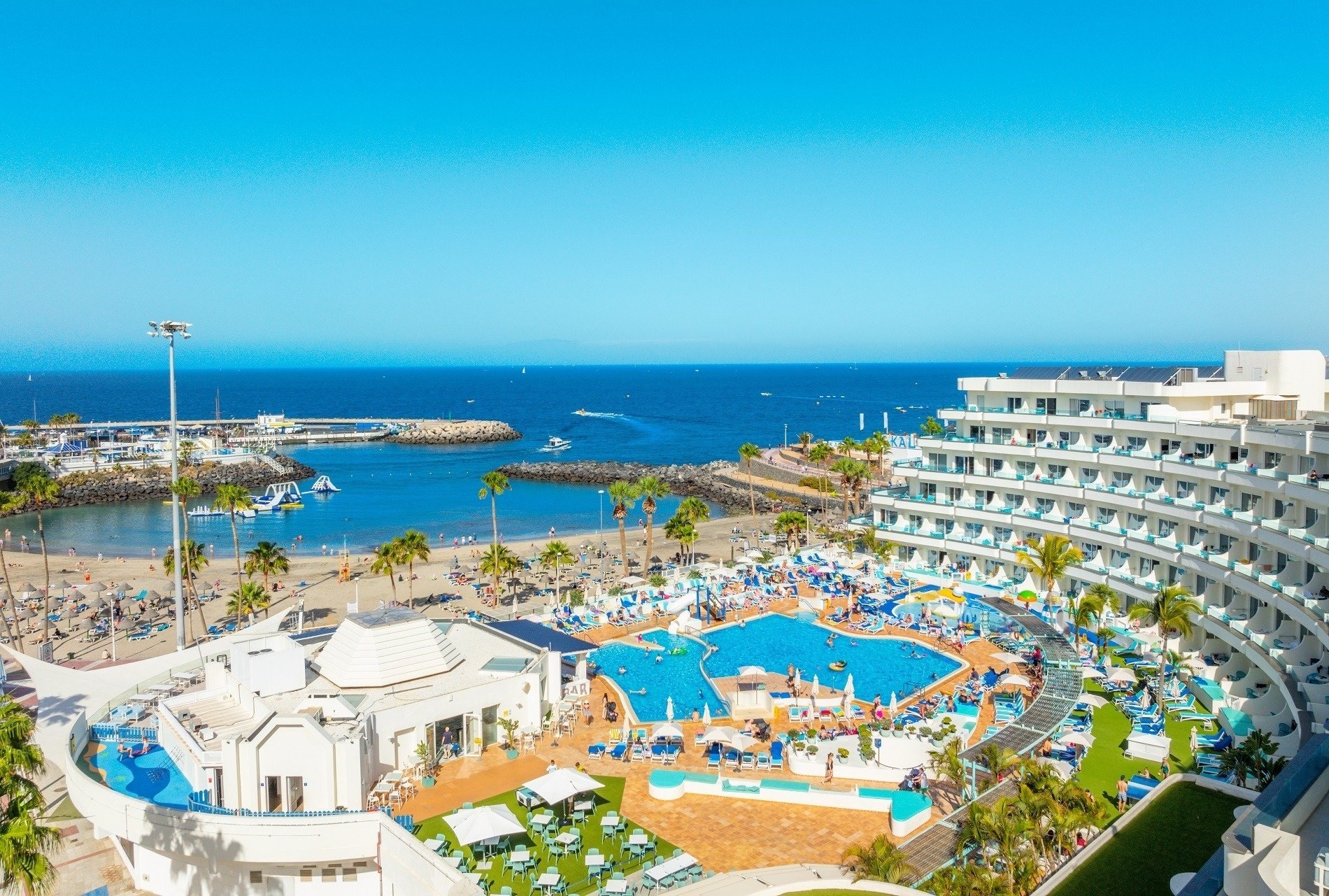 a large swimming pool in front of a hotel with the ocean in the background