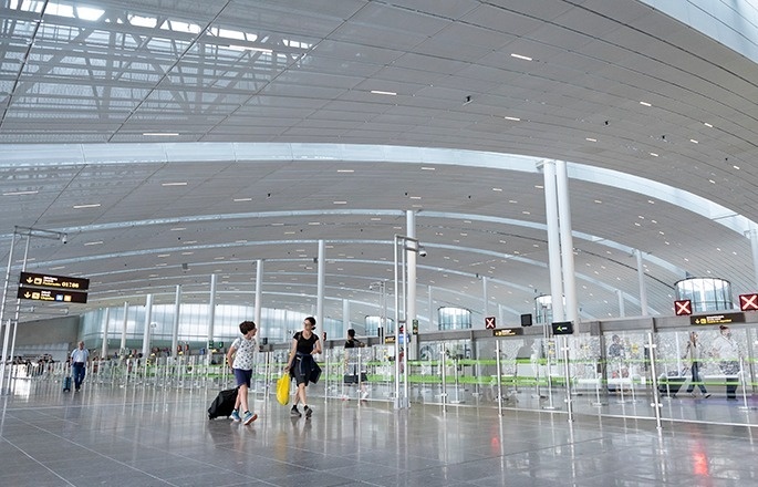 dos mujeres caminan por un aeropuerto con una maleta y un letrero que dice x