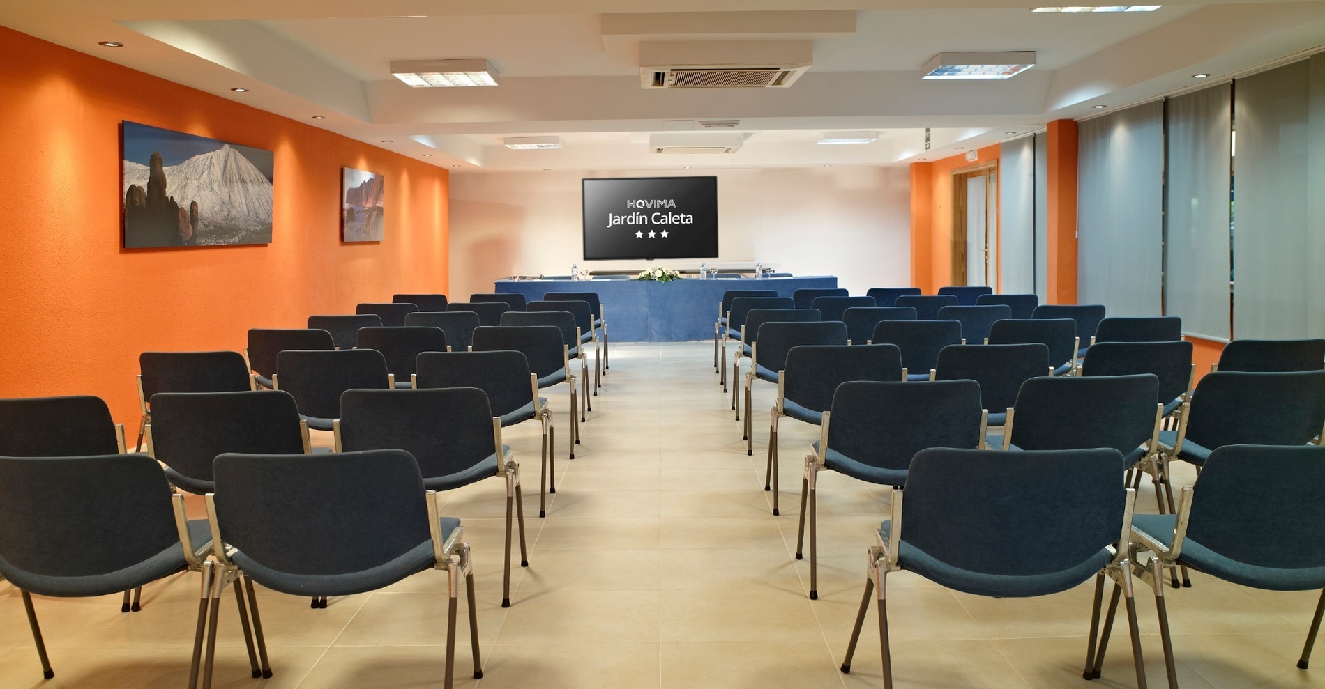 una sala de conferencias con sillas y una pantalla que dice hovita jardin celera