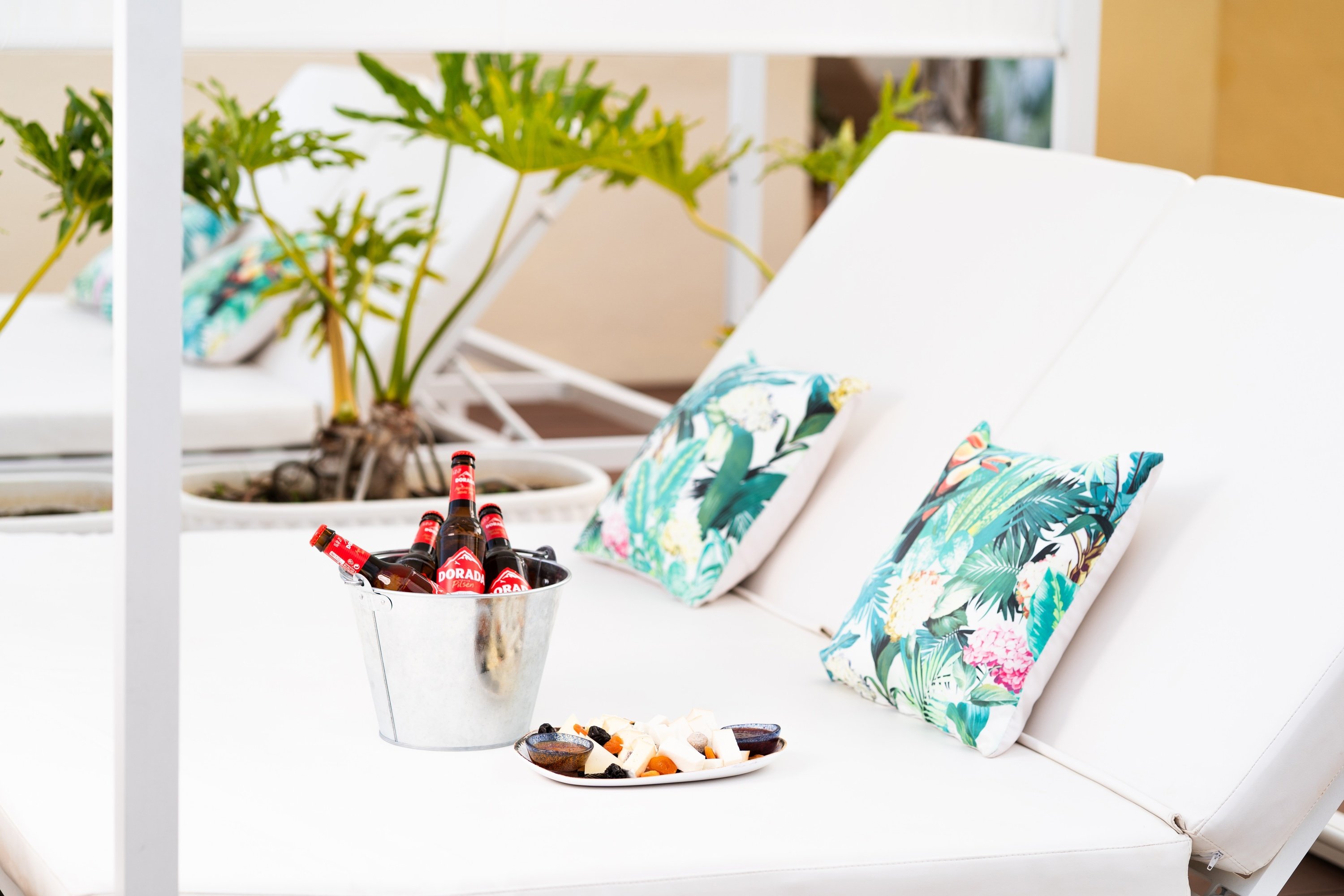 una tumbona blanca con almohadas tropicales en ella