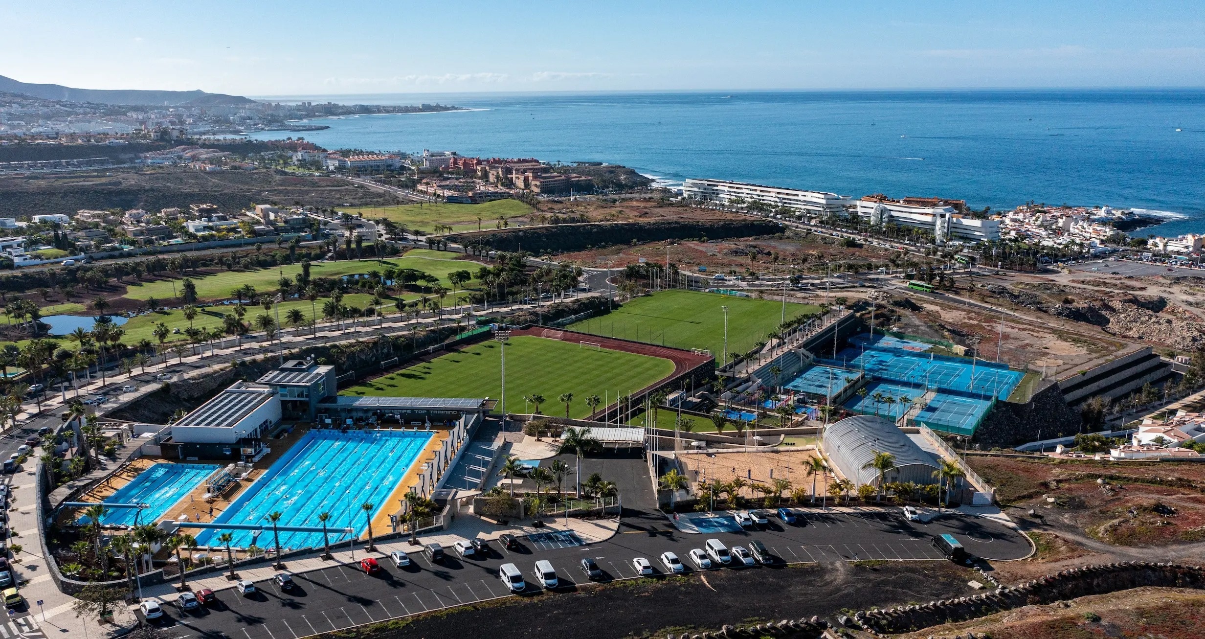 
                                    une vue aérienne d' un terrain de tennis et d' une piscine avec l' océan en arrière-plan