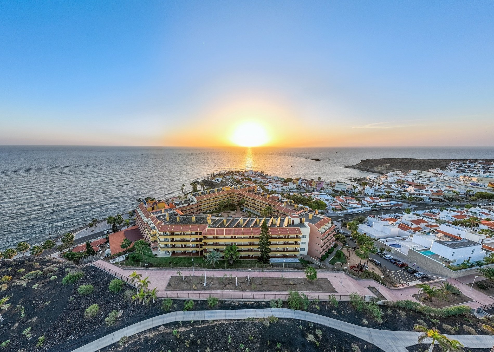 an aerial view of a city near the ocean at sunset