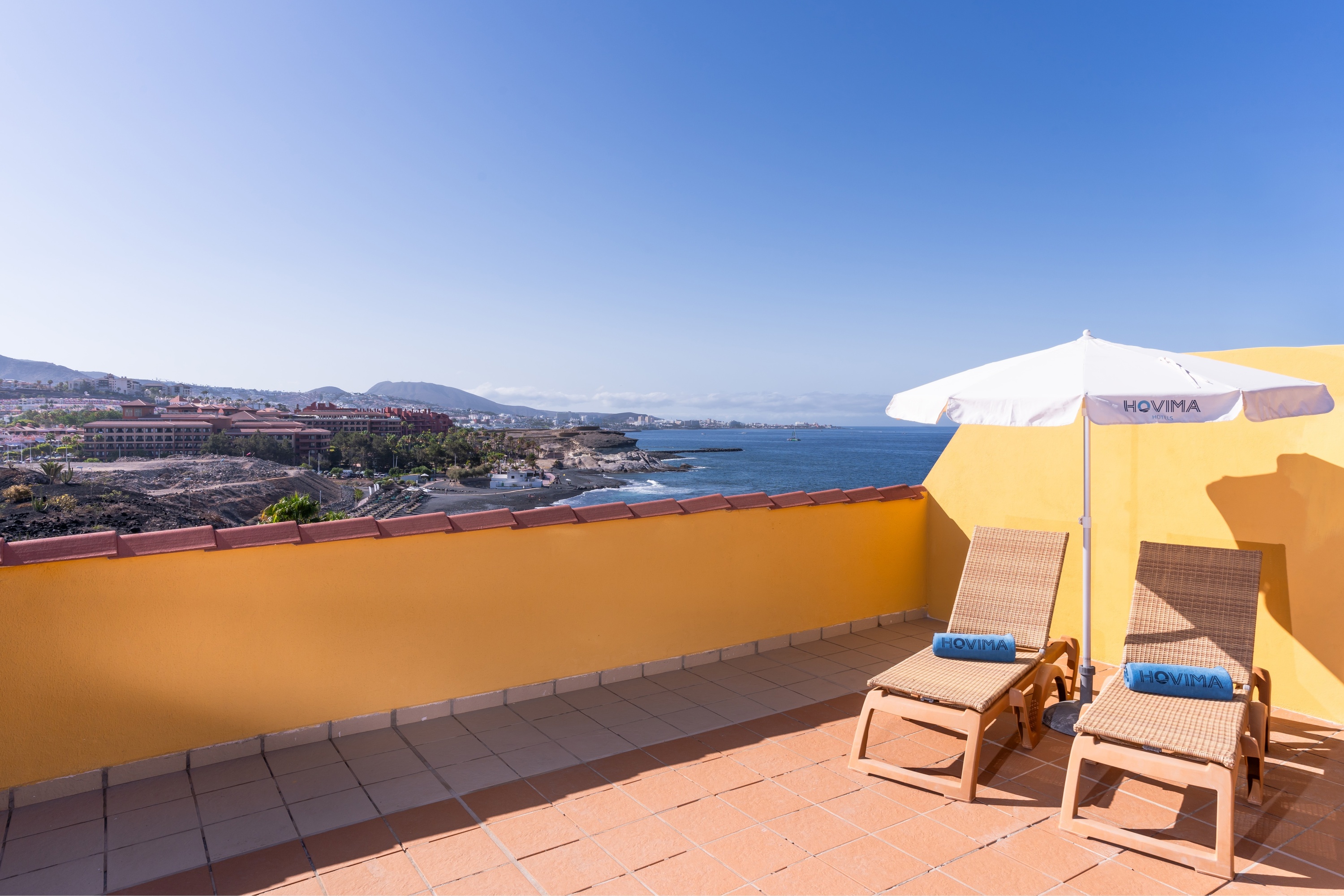 un balcón con sillas y un paraguas que dice hovuma