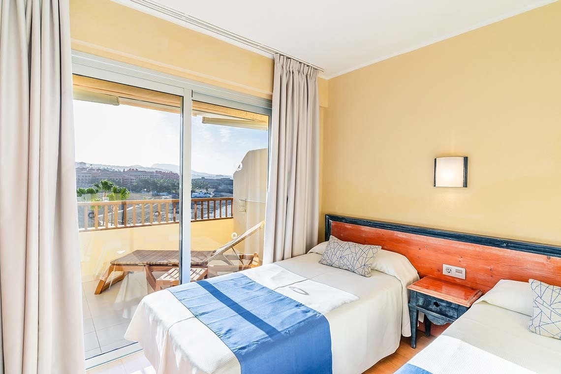 una habitación con dos camas y una puerta de vidrio que conduce a un balcón