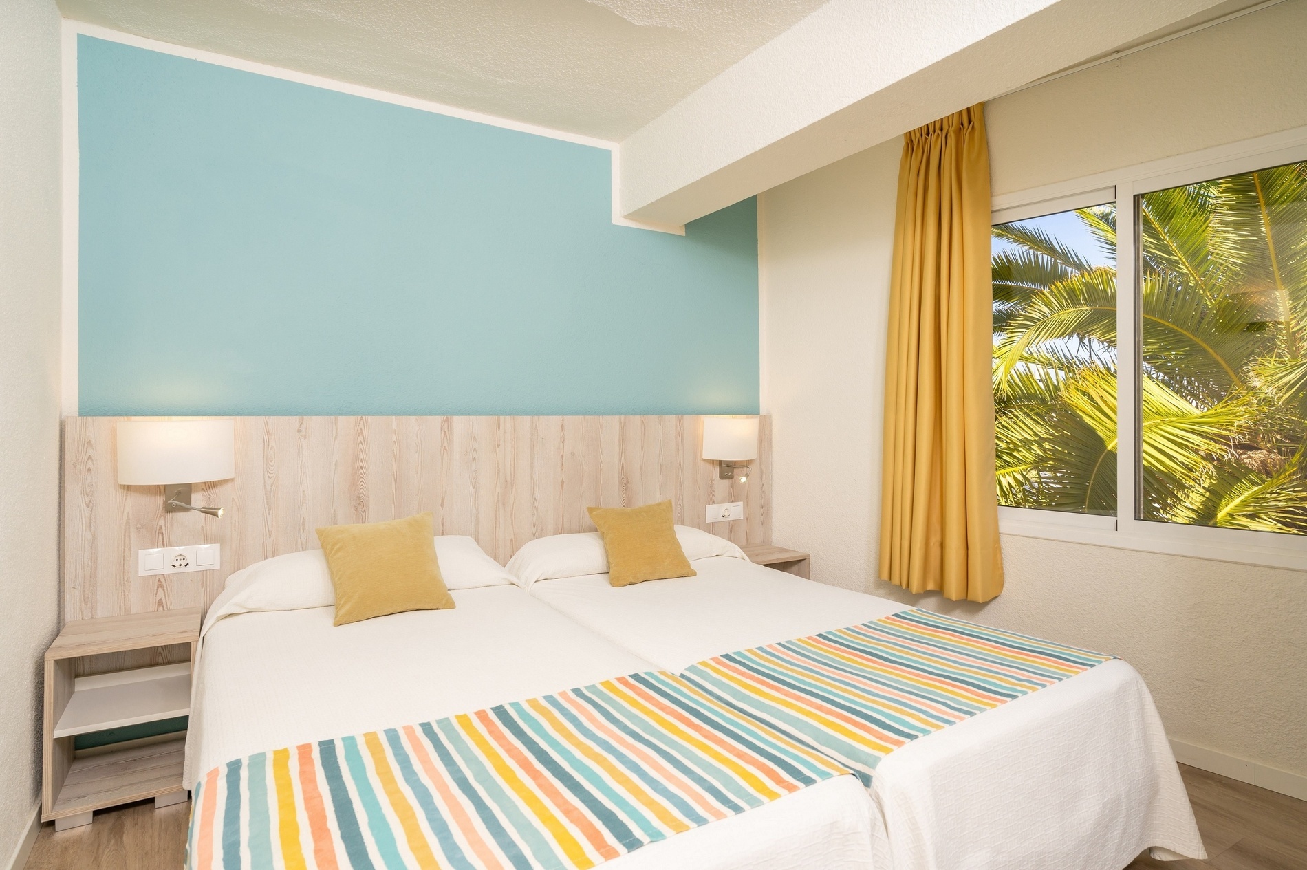 una camera d' albergo con due letti e cuscini colorati