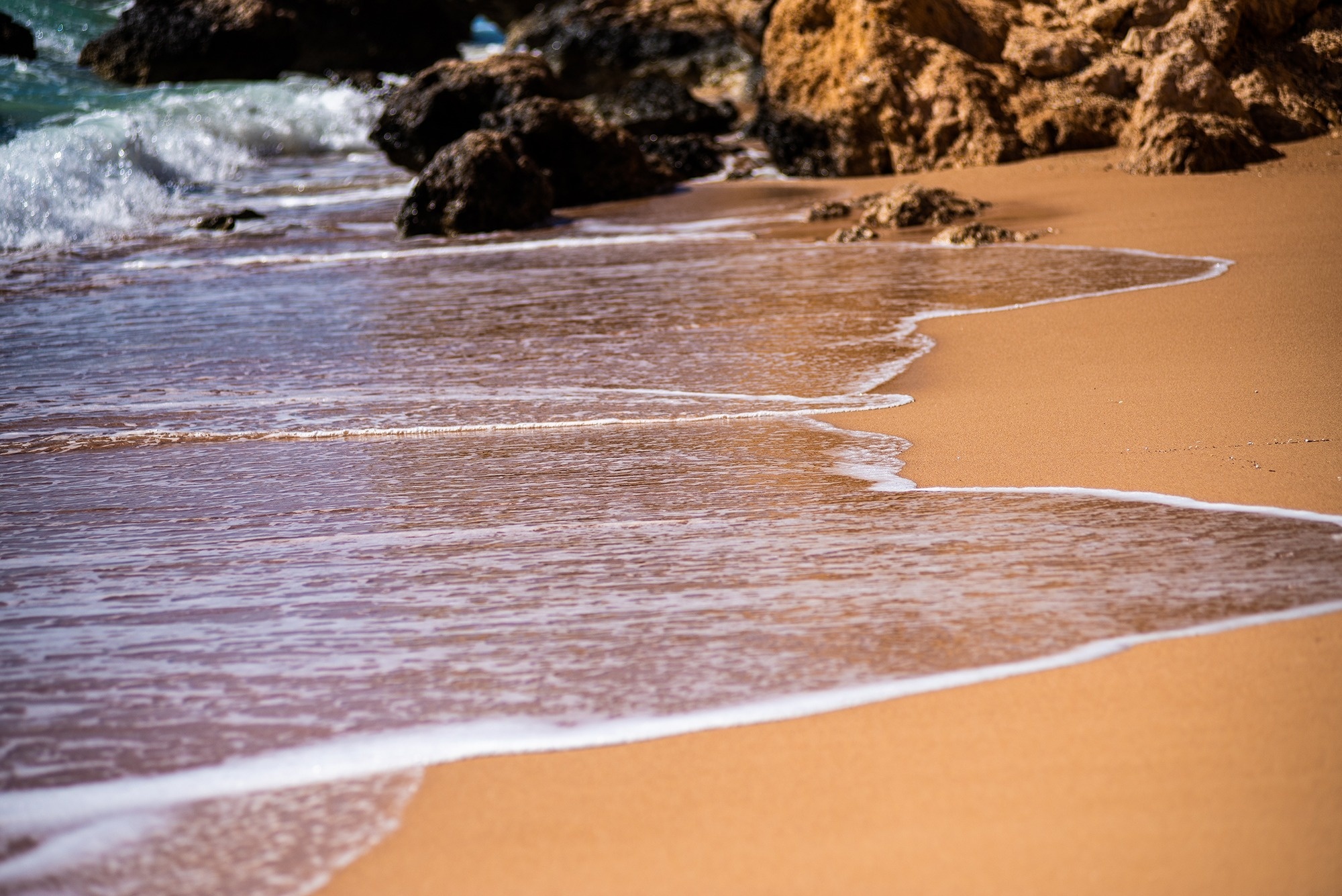 
                                    les vagues se brisent sur une plage de sable avec des rochers en arrière-plan