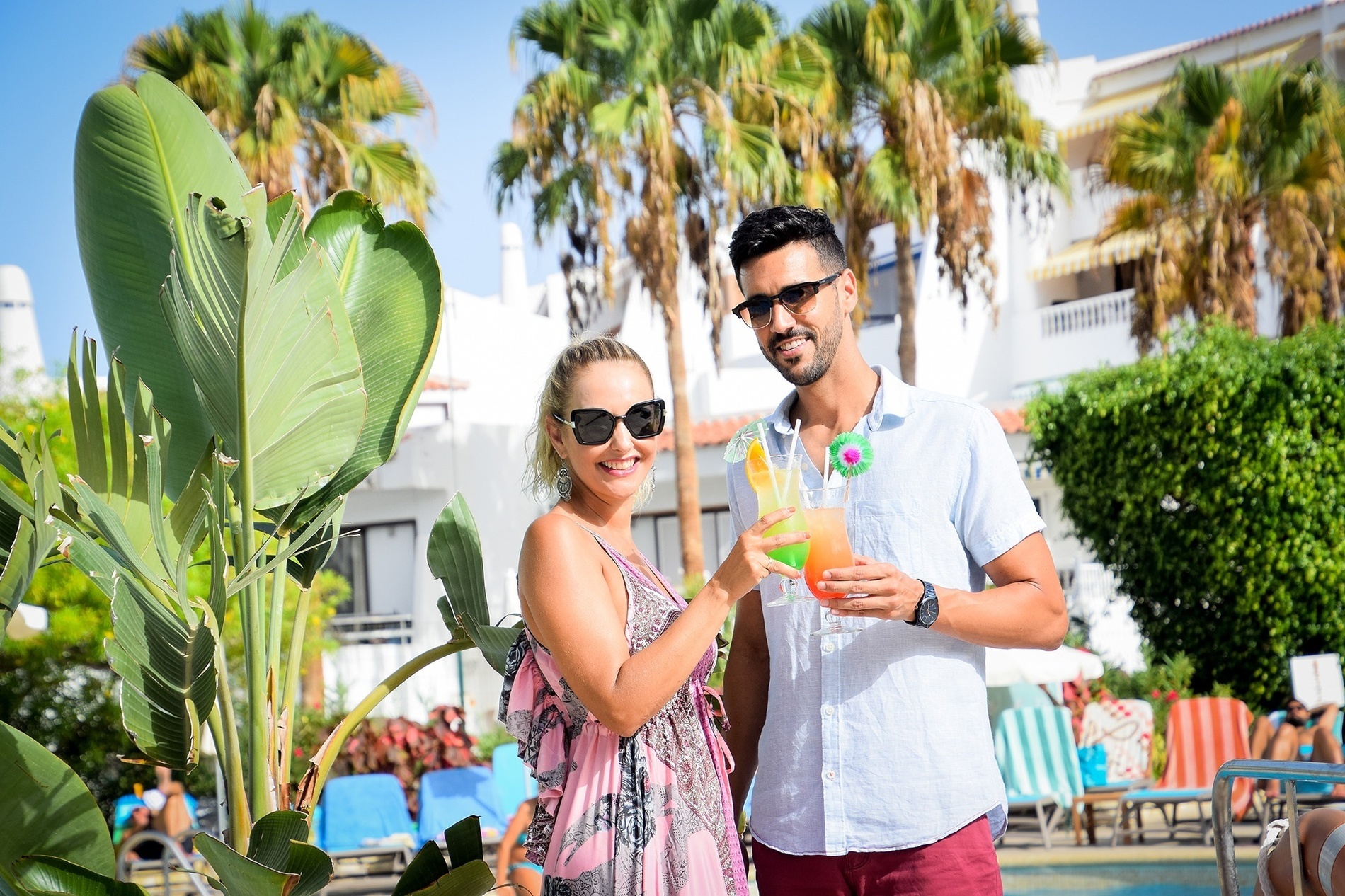 una grande piscina blu è circondata da palme e sedie a sdraio