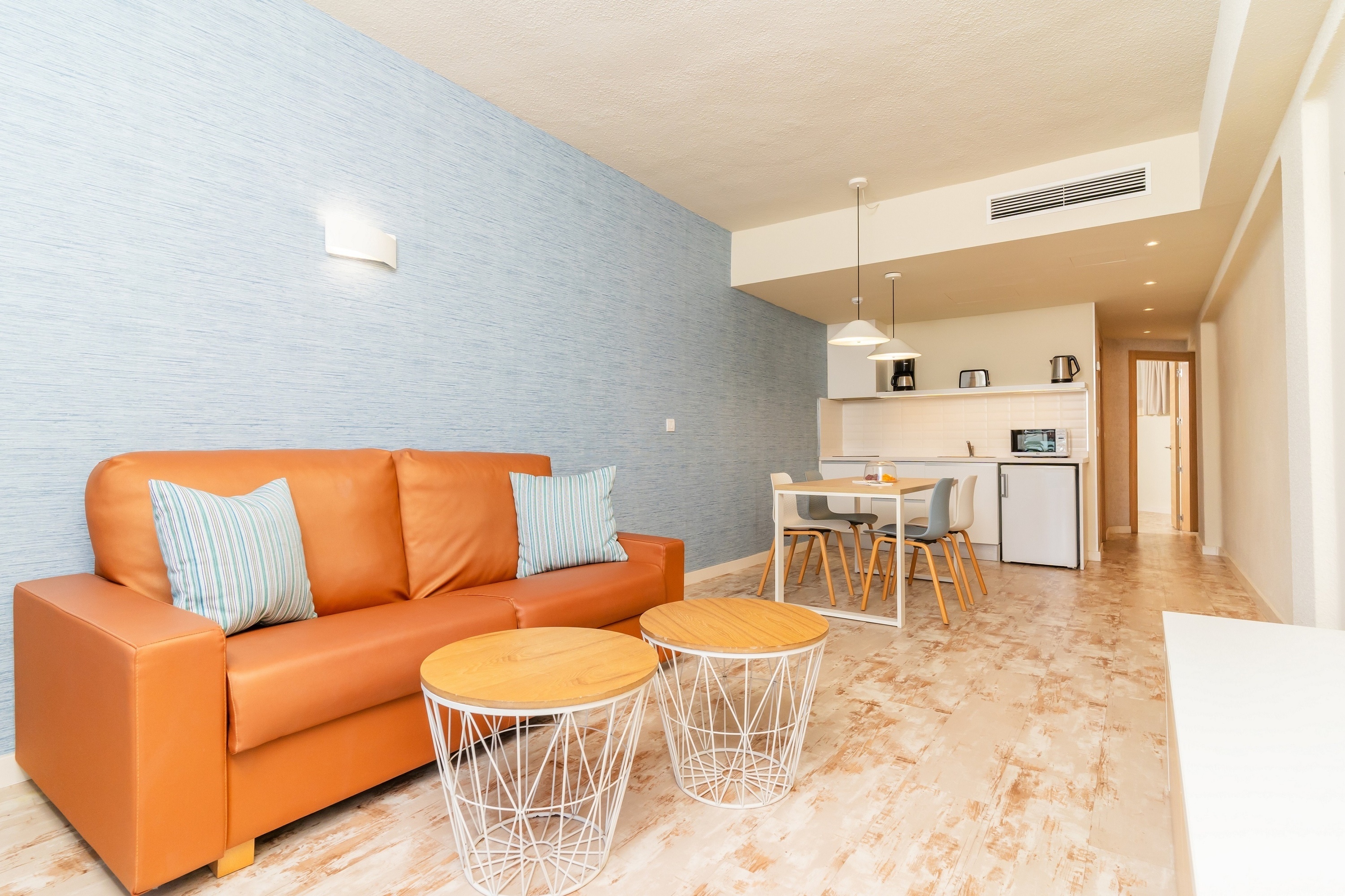 una sala de estar con un sofá naranja y una mesa blanca